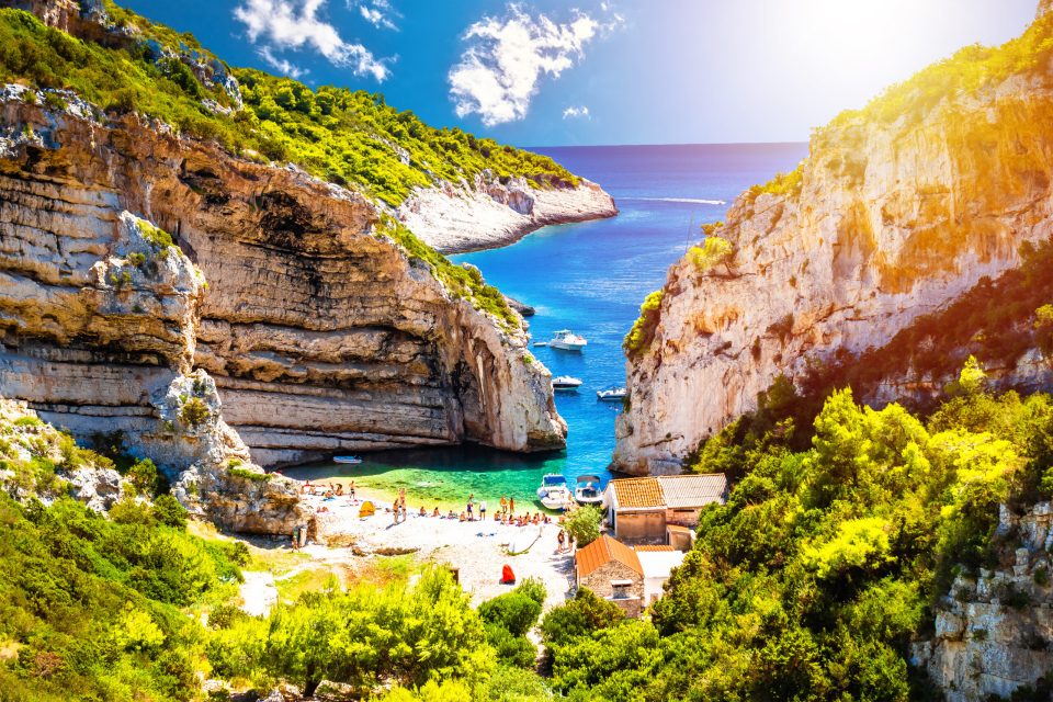 Scenic Stiniva beach on island of Vis sun haze view, Dalmatia archipelago of Croatia